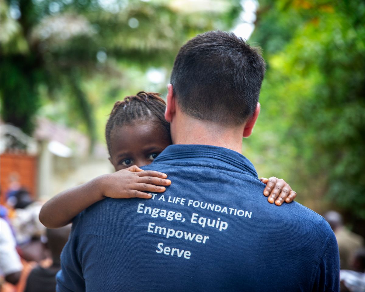 Volunteer with shirt saying, "Impact A Life Foundation: Engage, Equip, Empower, Serve
